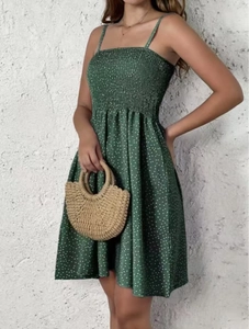 Detail of dark green polka dot sundress featuring a smocked bodice and thin straps