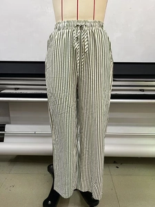 Detail view of elastic waist with adjustable drawstring on green striped wide leg pants