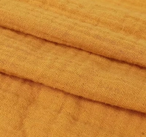 Close-up of mustard yellow double gauze fabric showing soft crinkled texture and weave