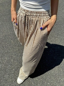 Detail of striped wide-leg pants featuring elastic drawstring waist and side pockets