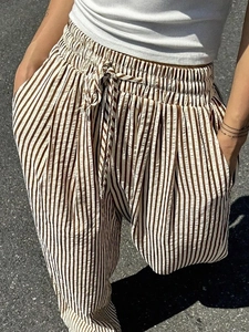 Detail of high waisted striped wide leg pants with drawstring waist and functional pockets