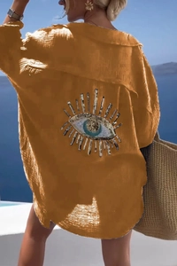 Detail of sequined Evil Eye embroidery on the back of yellow crinkle fabric shirt