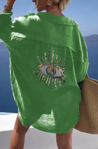 Detail of bohemian sequin evil eye embroidery on back of green cotton linen shirt