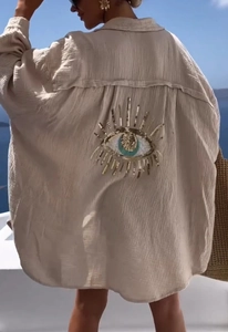 Detailed back view of a beige linen shirt featuring a large sequined evil eye embroidery