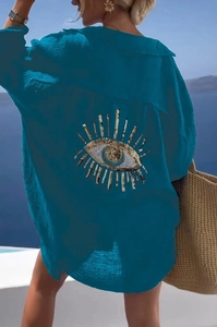 Detail of sequined evil eye embroidery on the back of a blue beach shirt cover-up