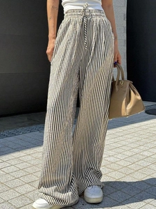Detail shot of high-waisted wide leg pants with black and white vertical stripes and drawstring