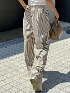 Detail of high waisted wide leg trousers featuring vertical stripes and elastic drawstring waist