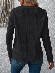 Detail view of the black knit long sleeve top featuring intricate chevron cutout texture