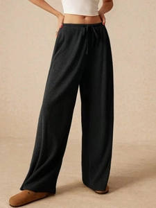 Dettaglio dei pantaloni neri a gamba larga con coulisse e tessuto in maglia a coste