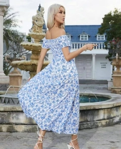 Detail van een bohemien maxi-jurk met blauwe bloemenprint, blote schouders en geplooide taille