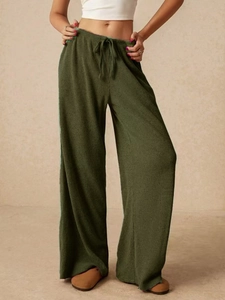 Dettaglio dei pantaloni a gamba larga verde scuro testurizzati con coulisse in vita