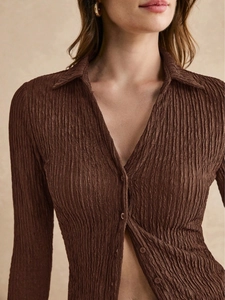 Detail of chocolate brown plissé blouse with vertical pleats and tonal button closure