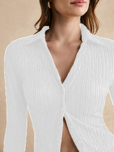 Detailed view of white pleated long-sleeve shirt showing v-neckline and button-down texture