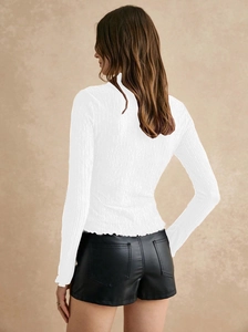 Rear view of long sleeve white textured shirt paired with black faux leather shorts