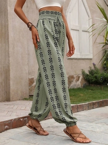 Detail of green harem pants featuring geometric prints, elastic waist, and drawstring