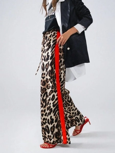 Detail von Leopardenmuster-Hose mit weitem Bein und roten Kontraststreifen seitlich