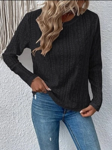 Detail shot of black knitted top featuring delicate cutout textures and geometric patterns