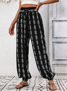 Detail of high-waisted harem pants featuring white geometric patterns and drawstring waist