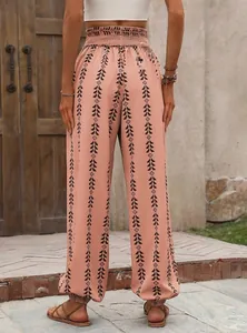 Detail view of high waist smocked waistband on orange geometric print joggers