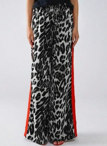 Detail einer weiten Hose mit Leopardenmuster und seitlichen roten Kontraststreifen