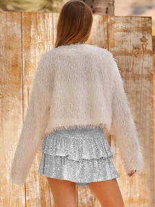 Detail of silver sequined tiered skirt with layered ruffles and textured knit top