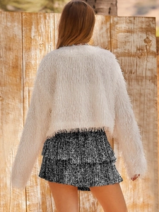 Close-up of black sequined layered mini skirt paired with white fluffy cardigan from behind