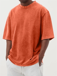 Close-up detail of oversized orange washed-out t-shirt with retro faded vintage texture