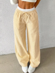 Detail of high-waisted wide-leg pants featuring yellow and white vertical stripes and drawstring