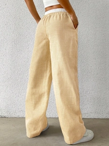 Detail view of high waisted wide leg trousers featuring light yellow vertical stripes