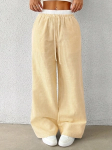 Detail of high waist striped wide leg pants with white elastic waistband and yellow drawstring