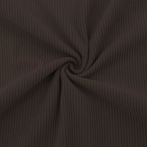 Gros plan sur un tissu en velours côtelé marron foncé montrant la texture douce striée