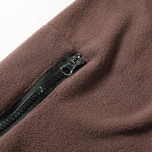 Close-up of brown fleece fabric texture with black zipper and silver metal puller