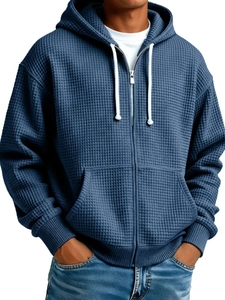 Macro view of blue waffle knit fabric on men's hoodie showing detailed texture and zipper
