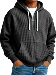 Detail of dark grey waffle knit hoodie featuring white drawstring and metal zipper closure