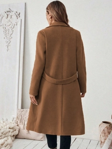 Detail van de decoratieve rugriem en naad op een bruine wollen jas voor dames