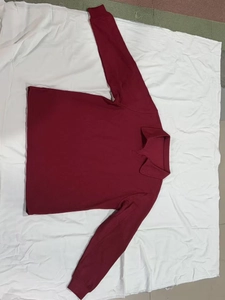 Detail eines weinroten Polohemds mit Waffelstrick-Struktur und Rippstrickbündchen