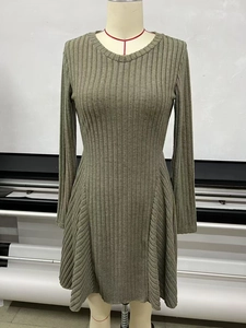 Detailed macro view of the olive green ribbed knit fabric and A-line hem on the dress