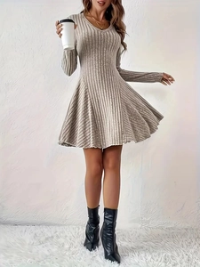 Detail of elegant beige knitted dress featuring a soft V-neck and ribbed texture fabric