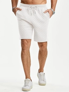 Detail view of men's white quilted shorts with drawstring waist and diamond pattern texture