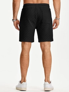 Detailed back view of men's black quilted sweatpants featuring diamond pattern and pocket