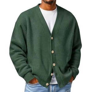 Detailed macro view of dark green waffle knit cardigan texture and beige contrast buttons