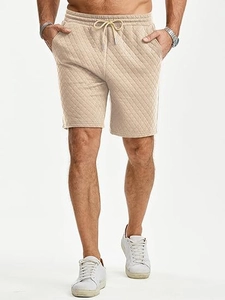 Detail of men's beige quilted sports shorts showing drawstring waist and diamond pattern