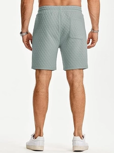 Detail view of quilted mint green casual shorts showing elastic waistband and back pocket