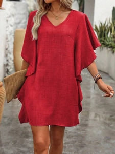 Détail macro d'une robe d'été rouge avec col en V, tissu texturé et manches volantées