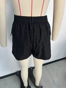 Detail van de hoge elastische tailleband en cargozak op zwarte korte broek