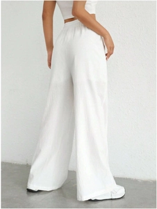 Detail view of white high-waisted trousers featuring textured crinkle fabric and elastic waist