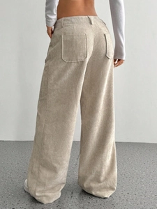 Dettaglio macro del tessuto a coste beige e delle tasche posteriori dei pantaloni larghi a vita alta
