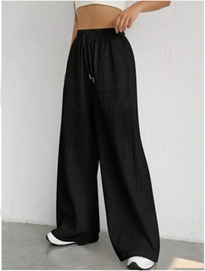 Detailed view of women's black drawstring wide leg pants with pockets and elastic waist