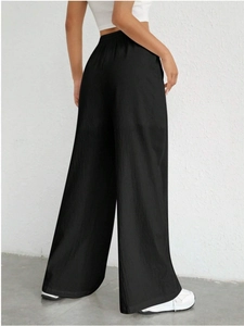 Detail of high waisted wide leg trousers showing elastic waistband and ribbed texture