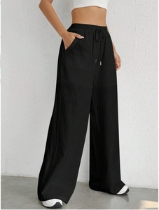Detail of black drawstring wide-leg pants with elastic waist and textured fabric